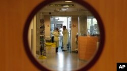 FILE - Doctors visit a patient at the intensive care unit of a children's hospital in Brussels, Nov. 25, 2013. 