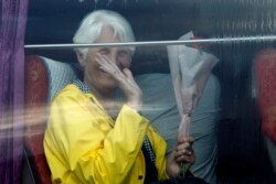 A passenger waves from a bus after she disembarked from the MS Westerdam, owned by Holland America Line, at the port of Sihanoukville, Cambodia, Friday, Feb. 14, 2020.