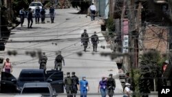FILE - Workers from the Ministry of Health are accompanied by soldiers and police as they investigate in a cordoned off neighborhood after multiple people tested positive for the new coronavirus, in Tegucigalpa, Honduras, March 17, 2020.