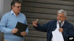 Mexico's president-elect Andres Manuel Lopez Obrador, right, flanked by his future foreign minister, Marcelo Ebrard, speaks to the press outside party headquarters in Mexico City, Mexico, July 22, 2018.