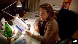 French journalist Ursula Gauthier, a reporter for the French news magazine L'Obs, holds a statement criticizing her from the Chinese Ministry of Foreign Affairs as she sits at her desk in her apartment in Beijing, Dec. 26, 2015.