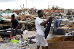 FILE - A man hangs his clothes after washing them at the Mudd neighborhood, devastated after Hurricane Dorian hit the Abaco Islands in Marsh Harbor, Bahamas, Sept. 6, 2019.