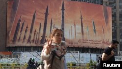 তেহরানের রাস্তায় ইরানি বাহিনীর ক্ষেপণাস্ত্রর বিলবোর্ড-এর সামনে পথচারী। ফটোঃ ১৫ এপ্রিল, ২০২৪। 