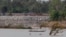 FILE - A fishing boat passes near a construction site of the Don Sahong dam, near the Cambodia-Laos border, June 20, 2016.