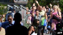 A group of pedestrians ask activists blocking the avenue to let them cross the street during clashes between opposition demonstrators and riot police in Caracas on July 10, 2017.
