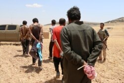 FILE - Men who Syrian Democratic Forces fighters claimed were Islamic State fighters walk as they are taken prisoner after the SDF advanced in the southern rural area of Manbij, in Aleppo Governorate, Syria, May 31, 2016.