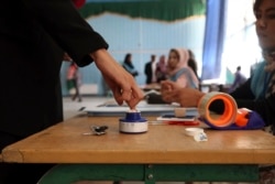 An Afghan woman, left, inks her finger at a polling station at Amani high school, near the presidential palace in Kabul, Afghanistan, Sept. 28, 2019.