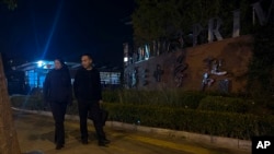 Plainclothes police officers pass by a primary school following a knife attack that occurred on an intersection road near a school in the northwestern Haidian district in Beijing, Oct. 28, 2024.