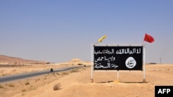FILE - A general view taken on Aug. 13, 2017, shows an Islamic State (IS) group sign in the central Syrian town of Al-Sukhnah. Pro-government fighters cleared the area after taking control of the county's large desert area called the Badiya.