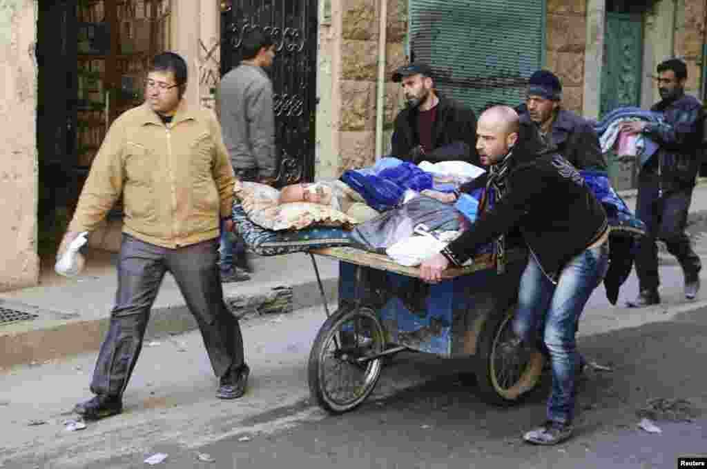 People wheel a sick man on a makeshift stretcher at the Karaj al-Hajez crossing, Aleppo, Feb. 9, 2014.&nbsp;
