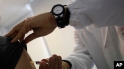 FILE - A doctor injects vaccine into a patient's arm, in Rome, Italy, Feb. 23, 2018.