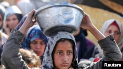 在哈马斯与以色列停火生效之前，巴勒斯坦人在加沙地带南部的汗尤尼斯聚集在一起，领取慈善厨房烹制的食物。(路透社：2025年1月17日)