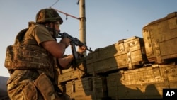 FILE - A Ukrainian government soldier fires toward Russia-backed rebel positions near Avdiivka, outside Donetsk, eastern Ukraine, Aug. 23, 2015.