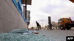 Arhiva - Radnik čisti polomljeno staklo ispred prodavnice 16. februara 2021. nakon raketnog napada prethodne noći, u glavnom gradu severne atuonomne oblasti iračkih Kurda.