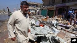 Civilians gather at the scene of a car bomb explosion in Baghdad's southwestern Amil neighborhood in Iraq, April 26, 2015. 