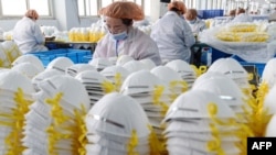 This photo taken on February 28, 2020 shows workers producing face masks at a factory in Handan in China's northern Hebei province.
