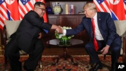 Le président des États-Unis, Donald Trump, serre la main du dirigeant nord-coréen Kim Jong Un lors de leurs premières rencontres au resort de Capella sur l'île de Sentosa, le 12 juin 2018 à Singapour.