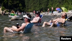 Beachgoers sit in the water at Alouette Lake to cool off during the scorching weather of a heatwave in Maple Ridge, British Columbia, Canada June 28, 2021. (REUTERS/Jennifer Gauthier)