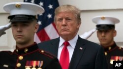 President Donald Trump stands behind and in front of members of a Marine honor guard as he greets Canadian Prime Minister Justin Trudeau and Sophie Gregoire Trudeau as they arrive at the White House in Washington, Oct. 11, 2017.