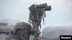 A service member of the Ukrainian armed forces uses binoculars while observing the area at fighting positions on the line of separation near the rebel-controlled city of Donetsk, Ukraine, April 6, 2021.