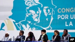 Leaders of the Revolutionary Armed Forces of Colombia (FARC), sit before former guerrillas as they lead the FARC's National Congress where they launched their political party in Bogota, Colombia, Aug. 27, 2017. The former leftist rebels have chosen a familiar-sounding acronym for their political movement: FARC, which now stands for "Common Alternative Revolutionary Force."