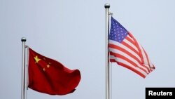 FILE - Chinese and U.S. flags flutter outside a company building in Shanghai, China April 14, 2021.