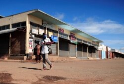 Seorang pria mengenakan masker saat berjalan melewati toko-toko yang tutup selama pemberlakuan restriksi (lockdown) untuk membatasi penyebaran virus COVID-19 di Harare, Zimbabwe, 28 Januari 2021.