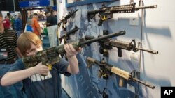 Un jovencito apunta con un fusil de asalto durante la convención anual de la NRA el fin de semana en Houston.