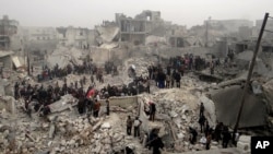 This citizen journalism image provided by Aleppo Media Center AMC shows people searching through the debris of destroyed buildings in the aftermath of a strike by Syrian government forces, in the neighborhood of Jabal Bedro, Aleppo, Feb. 19, 2013. 