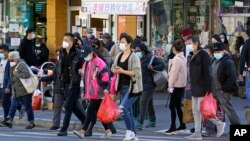 FILE - In this March 30, 2021, file photo, people cross a busy street in the shopping district of Flushing, a largely Asian American neighborhood in the Queens borough of New York. (AP Photo/Kathy Willens, File)