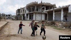 Des enfants jouent au football à proximité des bâtiments détruits dans des affrontements dans la ville historique de Bosra al-Cham, à Deraa, dans le sud de la Syrie, une ville tenue par des rebelles. (Photo prise le 23 février 2016).