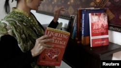 FILE - Maryam Suheyl, a marriage and family therapist, checks her books at her office in Lahore, Jan. 6, 2013.