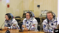 Actress Yulia Peresild, left, film director Klim Shipenko, right, and cosmonaut Anton Shkaplerov speak with their relatives through a safety glass prior the launch at the Baikonur Cosmodrome, Kazakhstan, Oct. 5, 2021.