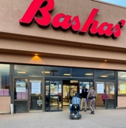 Navajo official and police officer assisting an elderly shopper for "Operation First of the Month" to keep them safe during COVID-19 outbreak.