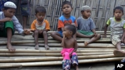 In this March 17, 2017, image made from video, Rosmaida Bibi, center foreground, suffering from severe malnutrition, sits on a pile of bamboo trees with other children at the Dar Paing camp, north of Sittwe, Rakhine state, Myanmar.