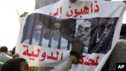An anti-Mubarak protester uses a shoe to beat an image of former president Hosni Mubarak along with his sons and former Interior Minister Habib al-Adli in front of the police academy where Mubarak is on trial in Cairo, Egypt, September 5, 2011.