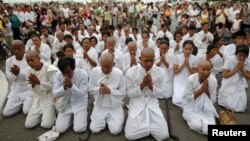 People wearing white pray as they mourn Cambodia's former King Norodom Sihanouk in front of the Royal Palace in Phnom Penh, October 15, 2012.