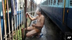 An Indian passenger takes a bath beside rail tracks on a hot summer day at a railway station in Jammu, India, Monday, May 25, 2015. Severe heat wave conditions continue to prevail at several places in northern India with temperatures reaching 48 degrees C
