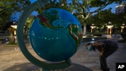 A resident wearing a mask against the coronavirus looks at a giant globe in Wuhan in central China's Hubei province, April 13, 2020. 
