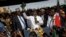 FILE - Opposition leader Raila Odinga, center, accompanied by lawyer Miguna Miguna, center-left, and others, holds a Bible aloft after a mock "swearing-in" ceremony at Uhuru Park in downtown Nairobi, Kenya, Jan. 30, 2018.