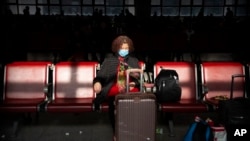 A traveler wears a face mask as she sits in a waiting room at Beijing West Railway Station in Beijing, Jan. 21, 2020. 