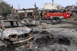 Firefighters stand near a fire rescue vehicle following clashes between people supporting and opposing a contentious amendment to India's citizenship law, in New Delhi, Feb. 26, 2020.