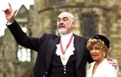 FILE - Sir Sean Connery, with wife Micheline (R), pose for photographers after he was formally knighted by the Britain's Queen Elizabeth at Holyrood Palace in Edinburgh July 5.