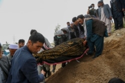 Mourners carry a covered dead body during a burial ceremony following a suicide attack in a maternity hospital, at a cemetery in Kabul, May 13, 2020.