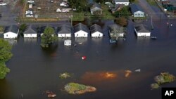 FILE - Floodwaters from Hurricane Florence surround homes in Dillon, S.C., Sept. 17, 2018. Scientists say climate change likely boosted rainfall totals for both Florence and 2017's Harvey. 