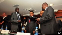 Nhial Deng Nhial, 2nd left, the head of South Sudan's negotiating team, and top negotiator for the rebel's side, Taban Deng Gai, right, a general in South Sudan's army before he defected, sign a cessation of hostilities agreement on Jan. 23, 2014.
