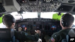 FILE - Lt. j.g. Kyle Atakturk, left, and Lt. j.g. Nicholas Horton, pilot a U.S. Navy P-8A Poseidon during a mission to assist in search and rescue operations for Malaysia Airlines flight MH370, March 19, 2014. 
