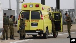 FILE - Israeli soldiers stand next to a military ambulance on a road near the West Bank Jewish settlement of Elkana, Nov. 15, 2022. A Palestinian killed two Israelis and wounded four others in an attack in a settlement before he was shot and killed by Israeli security personnel.