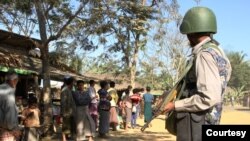 Seorang tentara Myanmar berdiri menjaga sekelompok pengungsi Rohingya di depan rumah mereka di sebuah desa di negara bagian Rakhine pada 25 Januari 2019. (Foto: AFP/Richard Sargent)
