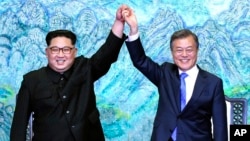 North Korean leader Kim Jong Un, left, and South Korean President Moon Jae-in raise their hands after signing a joint statement at the border village of Panmunjom in the Demilitarized Zone, South Korea, April 27, 2018.